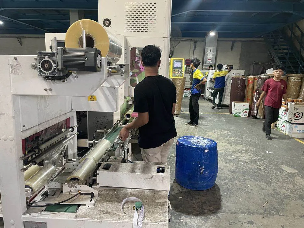 Karyawan mengoperasikan mesin produksi lakban di pabrik Harmony